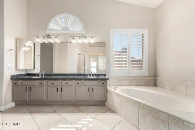 a large spacious bathroom with a granite countertop bathtub a sink and a large mirror