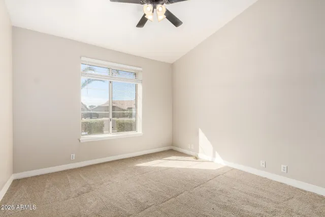 an empty room with a ceiling fan and windows