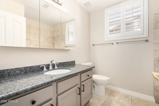 a bathroom with a granite countertop sink a toilet and a mirror