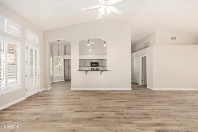 a view of kitchen and empty room with wooden floor