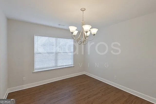 a view of a room with wooden floor chandelier and windows