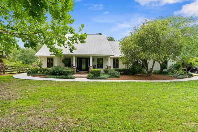 a front view of a house with a garden and trees