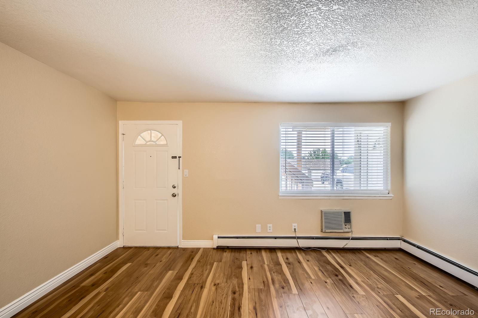 5402 Carr Street, Unit 102 Arvada, CO 80002 - Photo 6 of 27 an empty room with wooden floor and windows