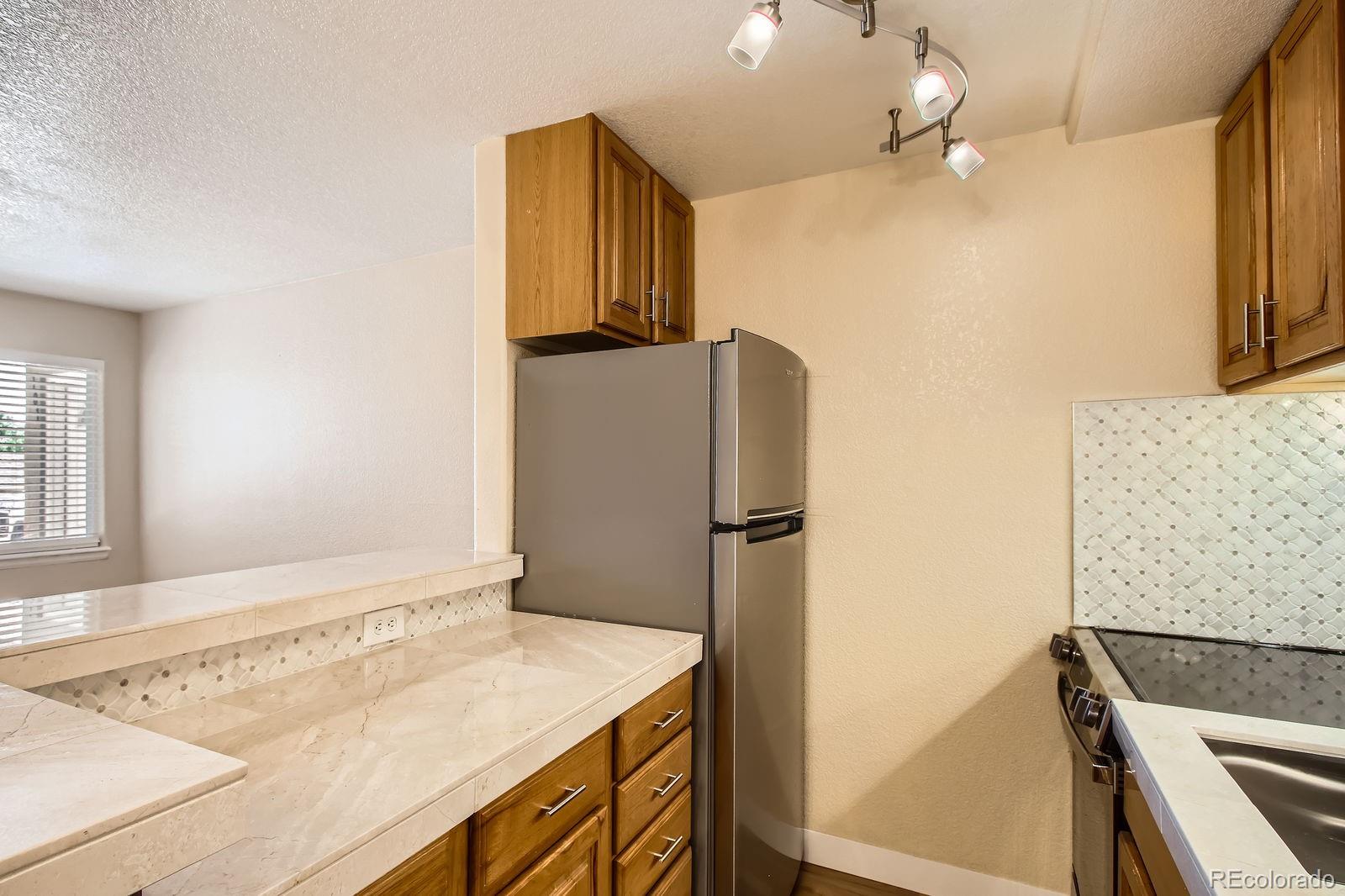 5402 Carr Street, Unit 102 Arvada, CO 80002 - Photo 7 of 27 a kitchen with a refrigerator and a sink