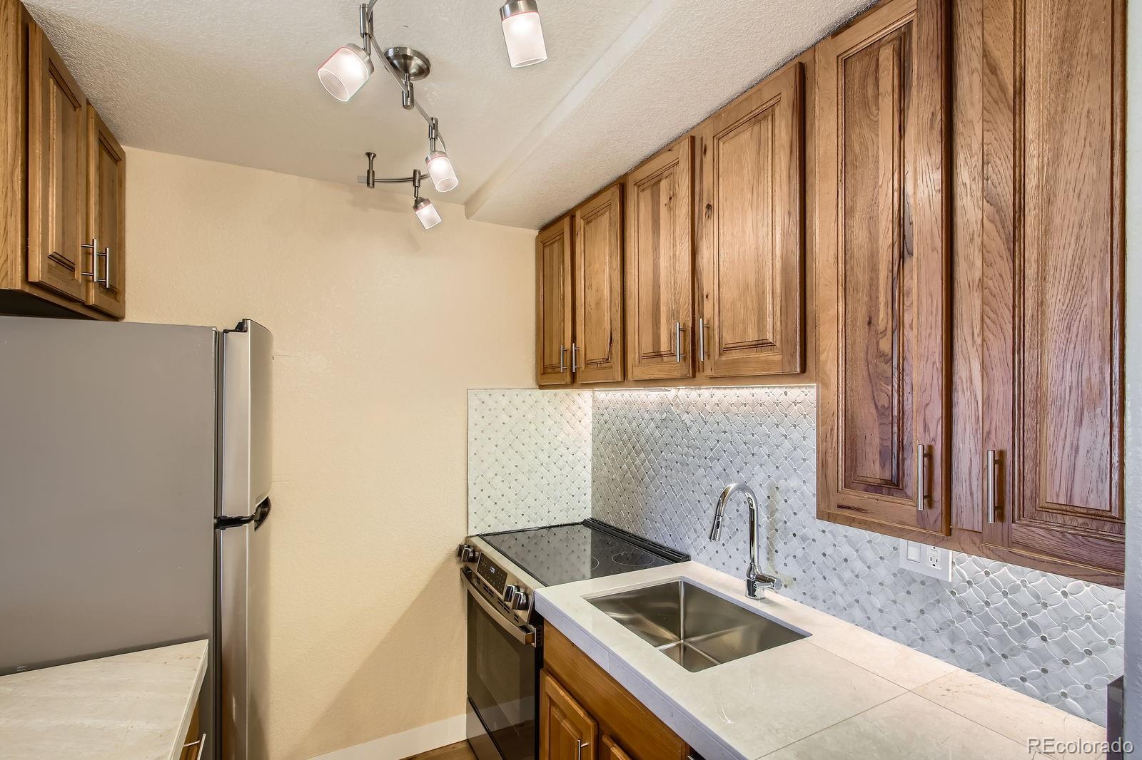 5402 Carr Street, Unit 102 Arvada, CO 80002 - Photo 8 of 27 a kitchen with stainless steel appliances granite countertop a sink a stove and a refrigerator