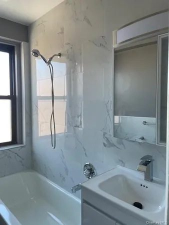 a bathroom with a tub sink and mirror