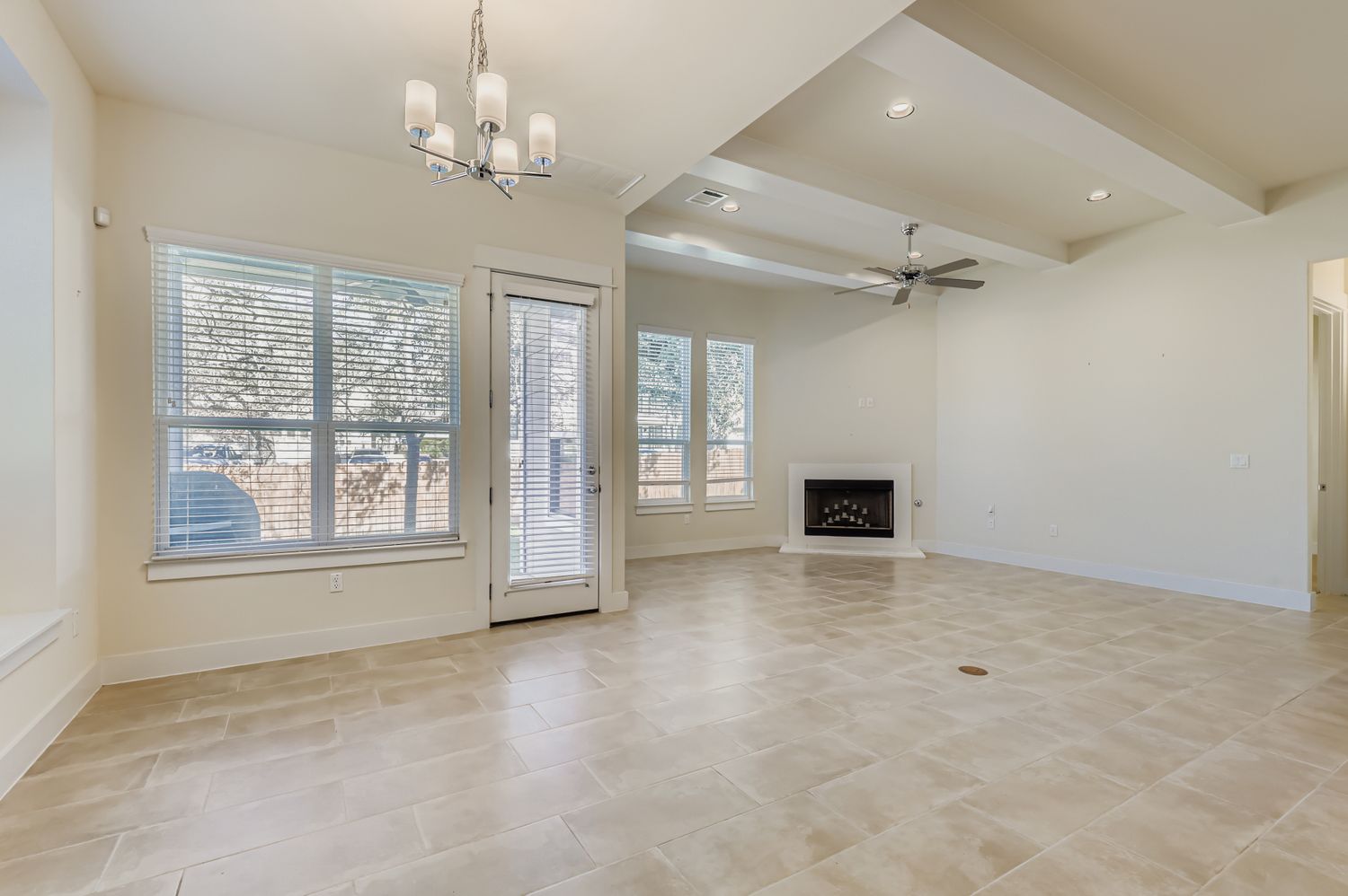 13116 Wingate Way Austin, TX 78727 - Photo 12 of 26 Unfurnished living room featuring beam ceiling, a fireplace with raised hearth, recessed lighting, a chandelier, and a ceiling fan