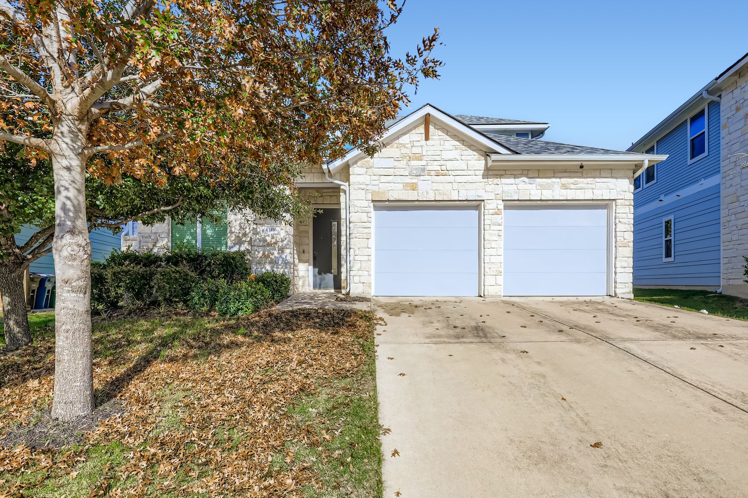 13116 Wingate Way Austin, TX 78727 - Photo 2 of 26 View of front of house featuring stone siding, driveway, and an attached garage