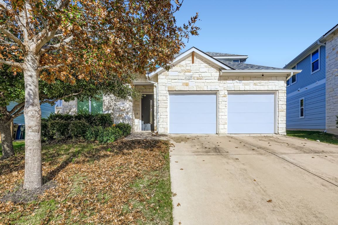 13116 Wingate Way Austin, TX 78727 - Photo 2 of 26 View of front of house featuring stone siding, driveway, and an attached garage