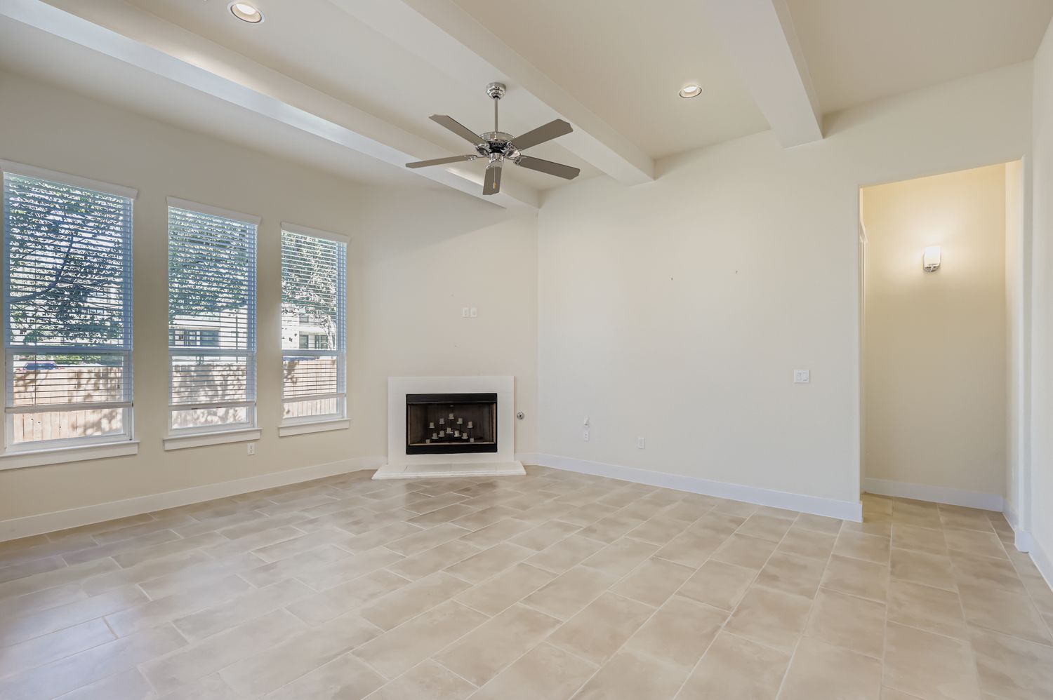 13116 Wingate Way Austin, TX 78727 - Photo 4 of 26 Unfurnished living room with a fireplace with raised hearth, recessed lighting, ceiling fan, and beam ceiling