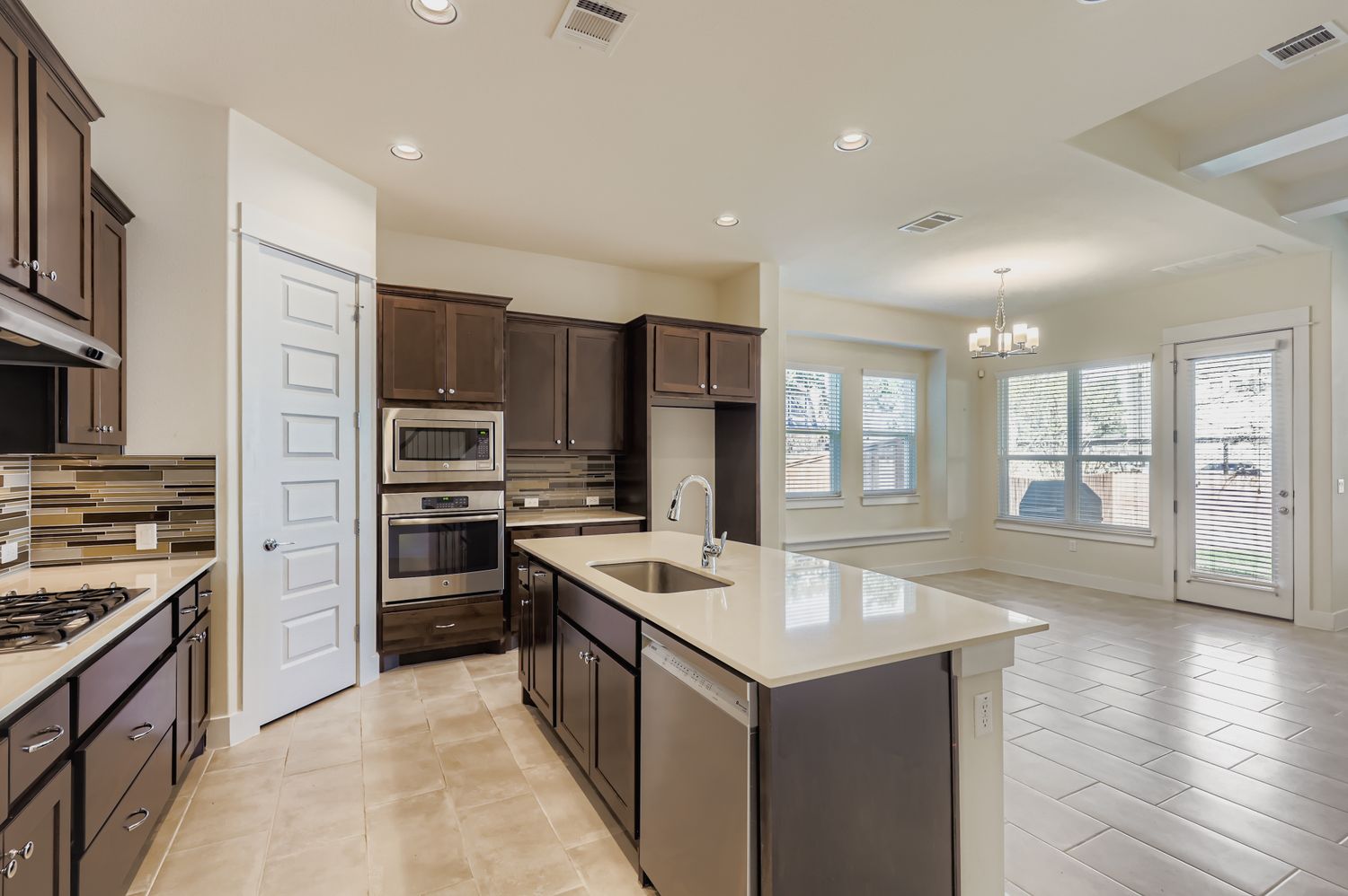 13116 Wingate Way Austin, TX 78727 - Photo 10 of 26 Kitchen featuring backsplash, dark brown cabinetry, stainless steel appliances, light stone countertops, and recessed lighting
