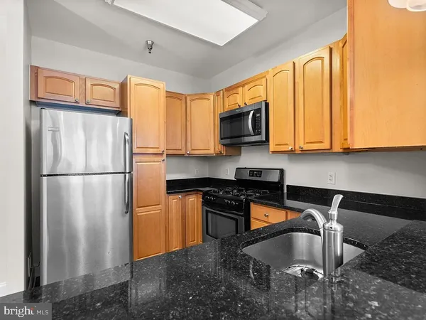 a kitchen with stainless steel appliances granite countertop a refrigerator a stove a sink and a microwave