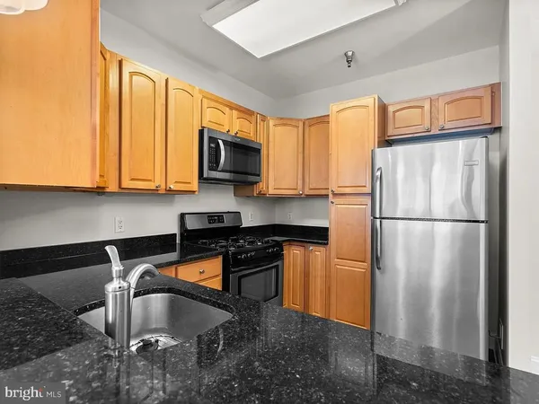 a kitchen with stainless steel appliances granite countertop a refrigerator a stove a sink and a microwave