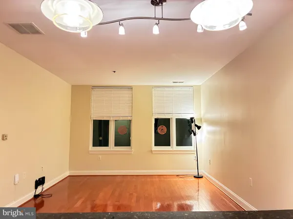 a view of an empty room with window and wooden floor
