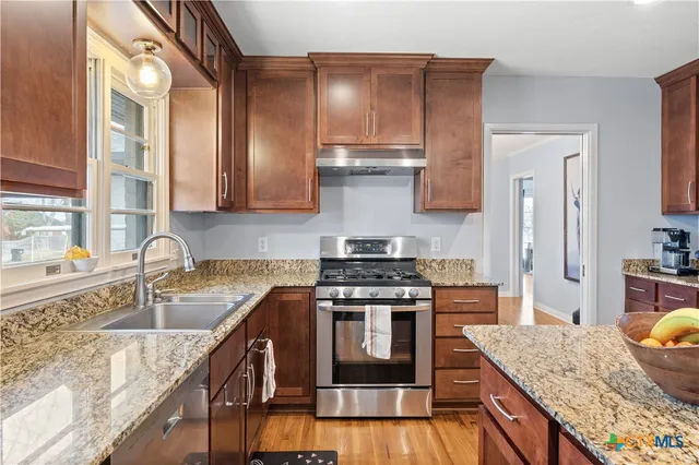 a kitchen with stainless steel appliances granite countertop a sink stove and refrigerator
