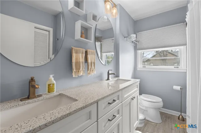 a bathroom with a granite countertop toilet sink and mirror