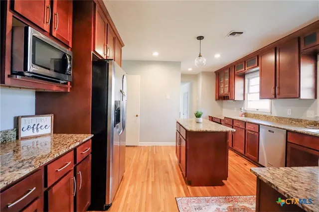 a kitchen with stainless steel appliances granite countertop microwave stove top oven and cabinets