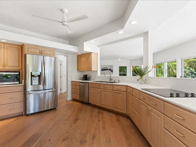 a large kitchen with a refrigerator a sink dishwasher stove and white cabinets