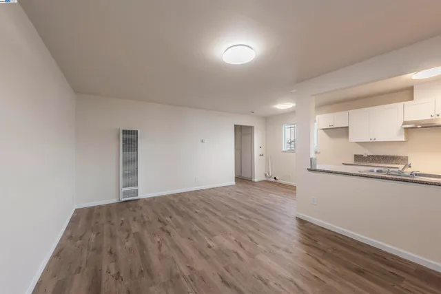a big room with wooden floor and kitchen view