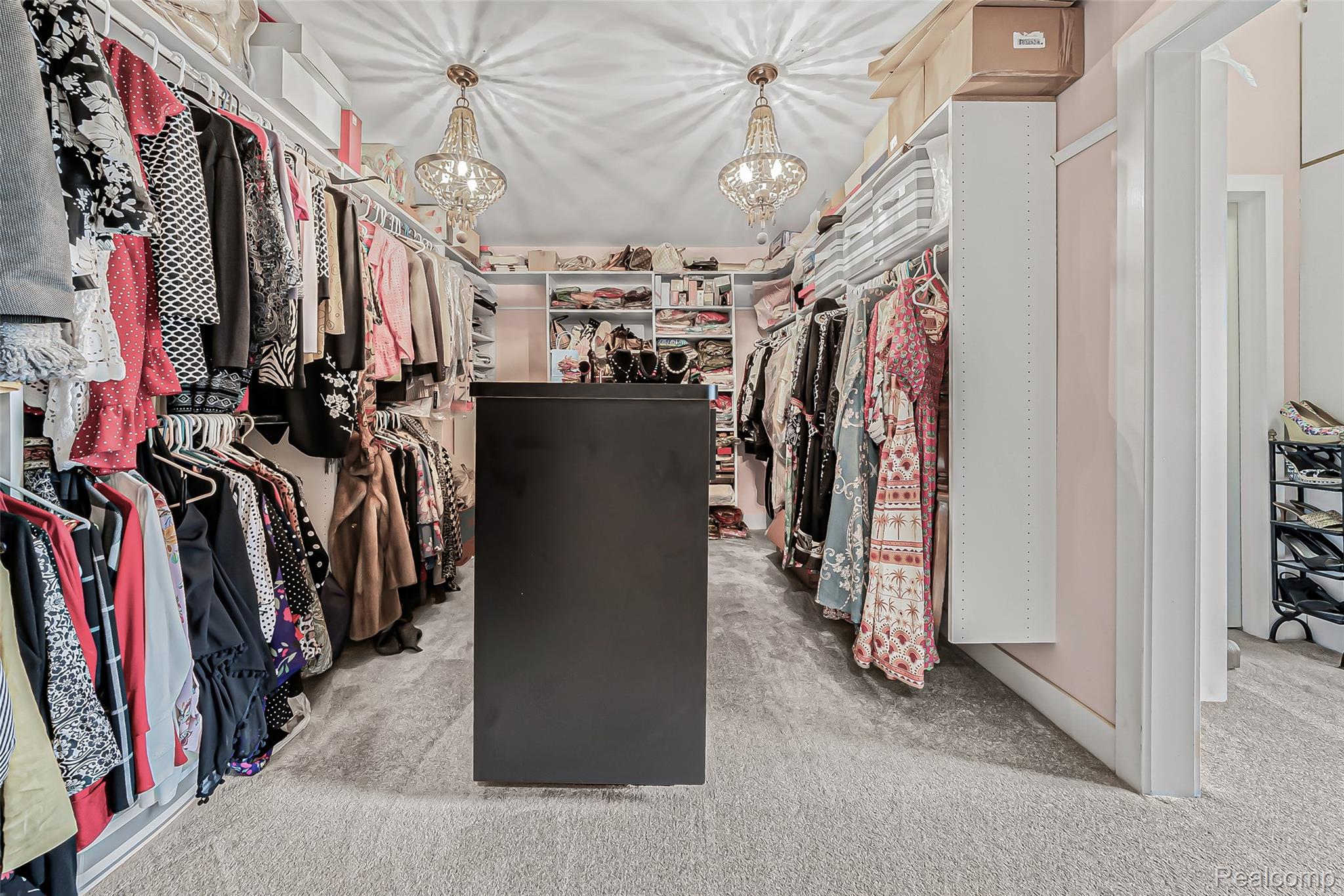 2785 Cranbrook Ridge Court Rochester, MI 48306 - Photo 37 of 99 Spacious walk-in closet featuring extensive built-in shelving, hanging rods, an integrated storage island, and two decorative chandeliers