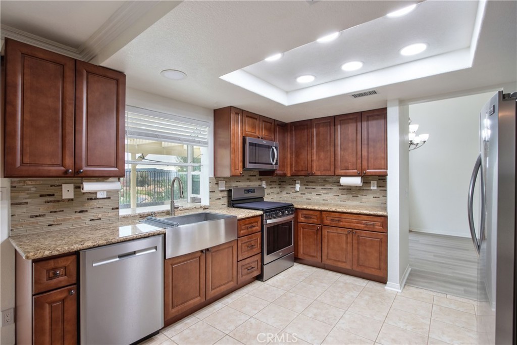 24055 Golden Pheasant Lane Murrieta, CA 92562 - Photo 12 of 38 a kitchen with stainless steel appliances granite countertop wooden cabinets a sink and dishwasher a refrigerator with wooden cabinets