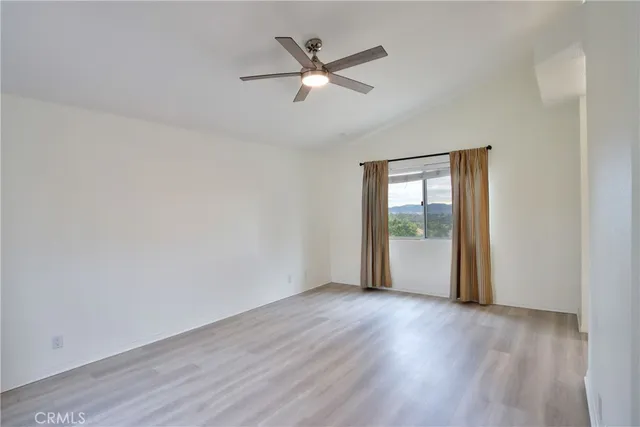 an empty room with wooden floor and ceiling fan