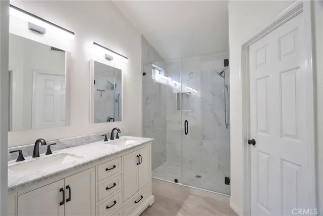 a bathroom with double sink shower and two mirror