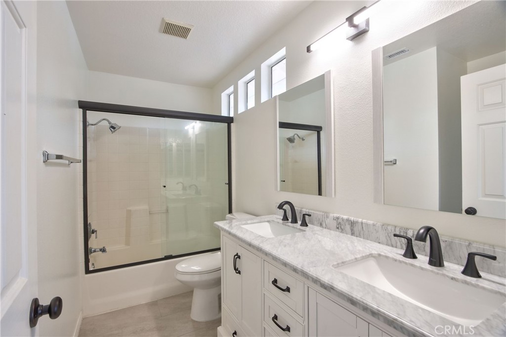 24055 Golden Pheasant Lane Murrieta, CA 92562 - Photo 27 of 38 a bathroom with a granite countertop sink toilet a shower and a mirror