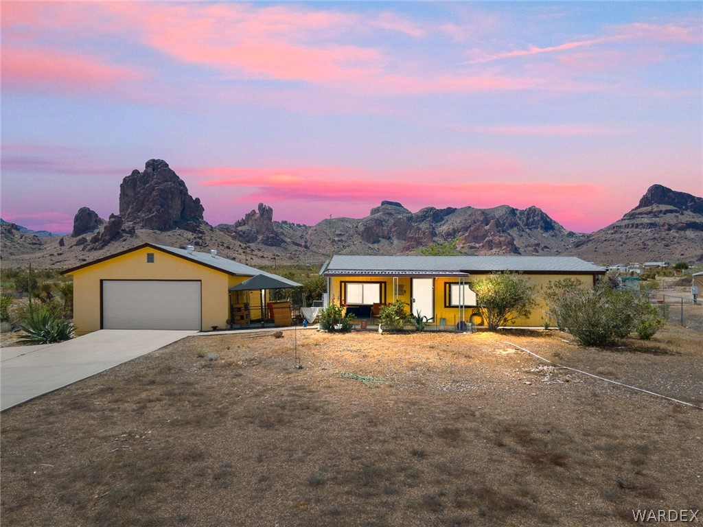 2465 Egar Road Golden Valley, AZ 86413 - Photo 1 of 98 The property features a yellow exterior and an attached garage with a concrete driveway