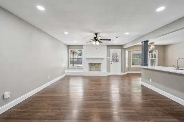 a view of an empty room with wooden floor and a fireplace