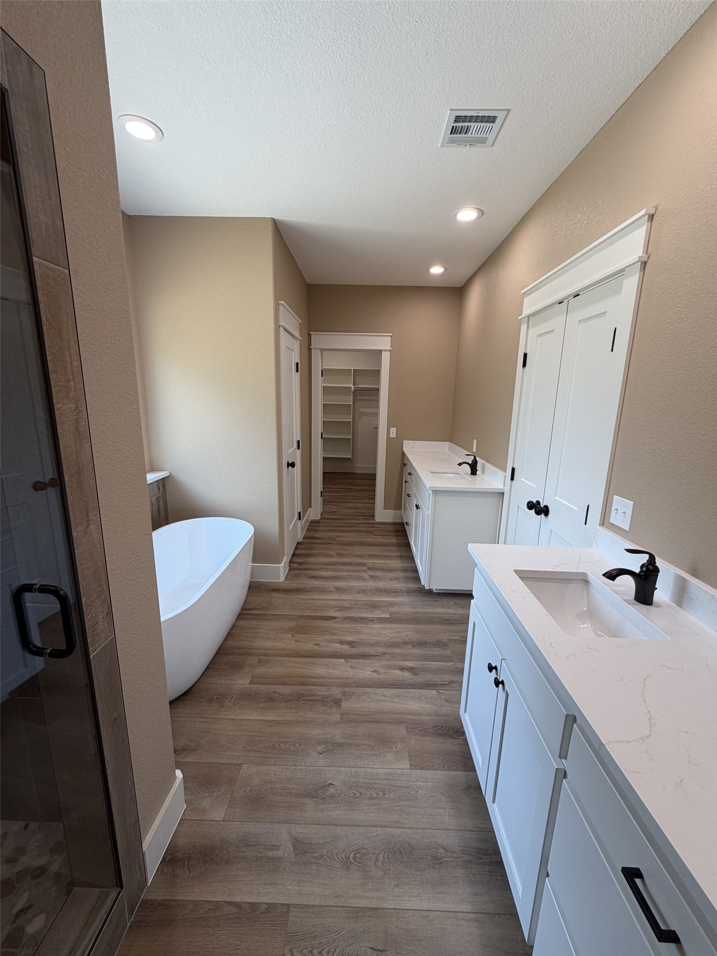 33 Wilderness Road North Calera, OK 74730 - Photo 11 of 39 Dual vanity sinks with white cabinetry, wood-finish flooring, a standalone soaking tub, and recessed lighting