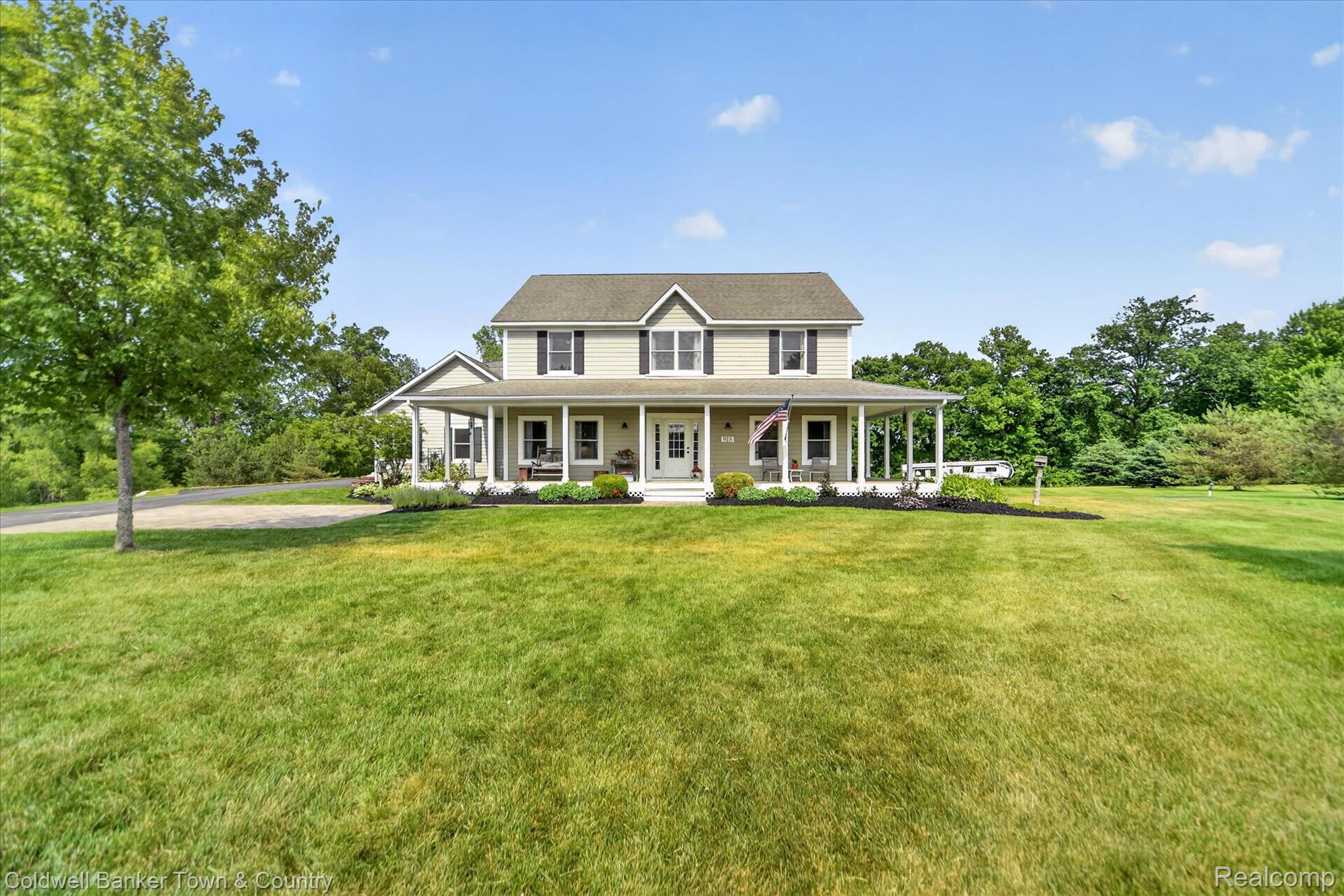 918 Gray Fox Court Howell, MI 48843 - Photo 2 of 84 Traditional-style residence featuring a broad front lawn, a wraparound porch with white columns, light-colored siding, dark shutters, and a prominent front door