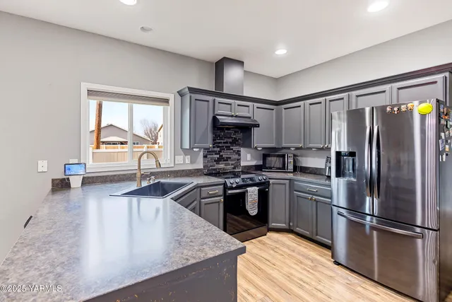 a kitchen with kitchen island granite countertop a sink stainless steel appliances and cabinets