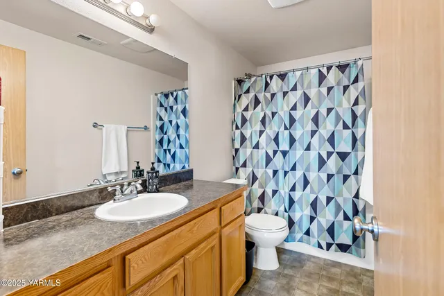a bathroom with a granite countertop sink a toilet and a shower curtain