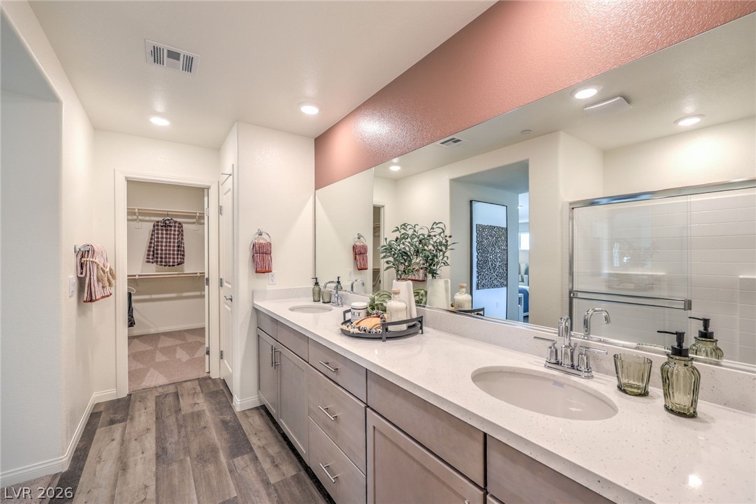 1017 Copper Robin Street Henderson, NV 89011 - Photo 23 of 43 Bathroom with wood finished floors, a spacious closet, double vanity, a shower with door, and recessed lighting. Photo is representational only; actual home finishes may vary.