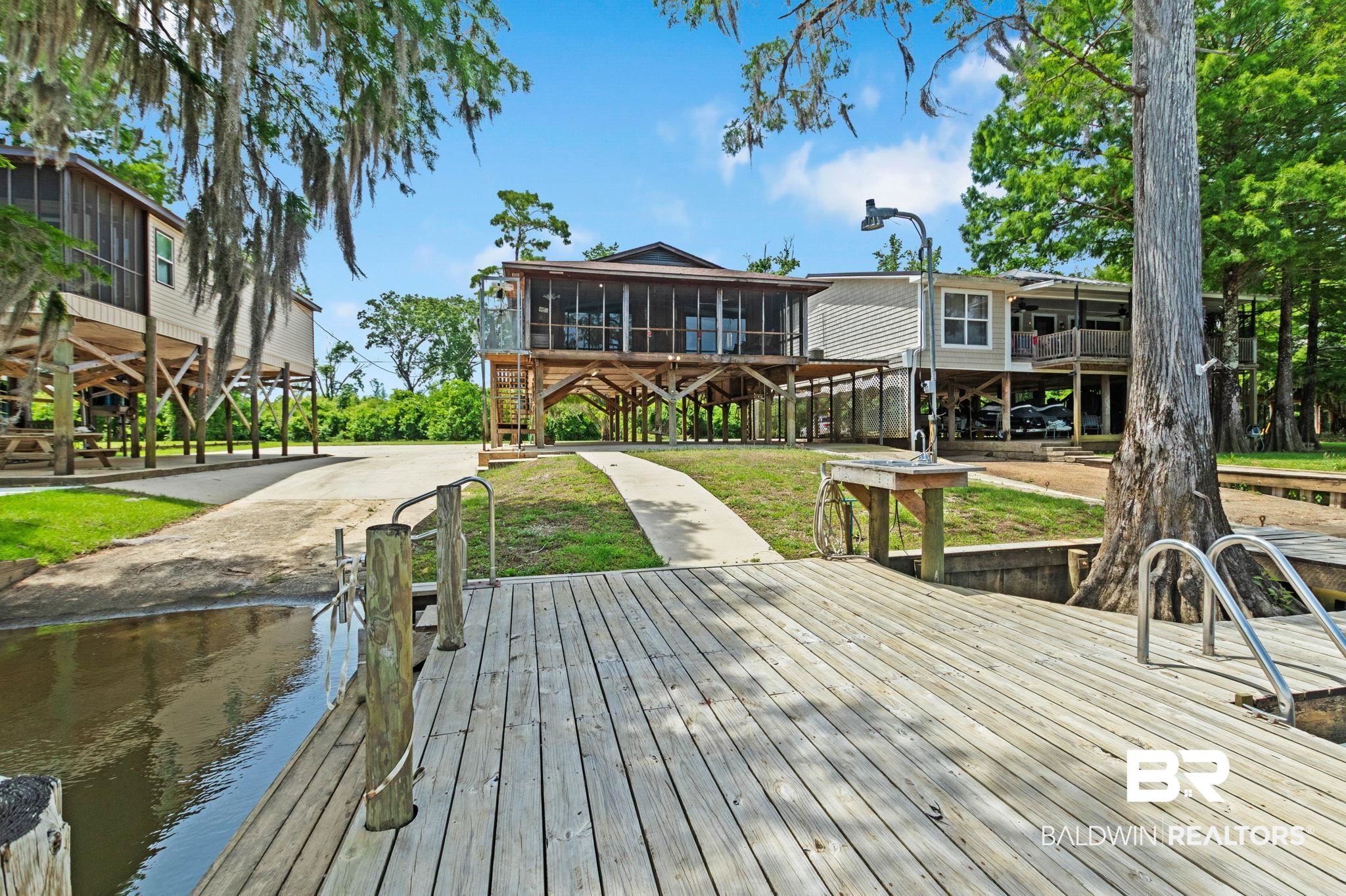 8153 Bryant's Lndg Road Stockton, AL 36579 - Photo 56 of 87 Expansive outdoor deck with a built-in ladder for water access, a utility sink, and wood pilings
