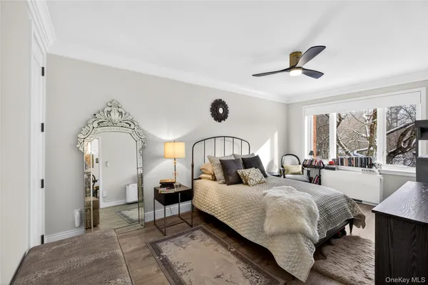 a bedroom with a bed a mirror on the dresser and a large window