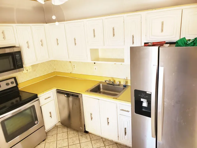 a kitchen with a refrigerator a stove a sink dishwasher and wooden cabinets with wooden floor