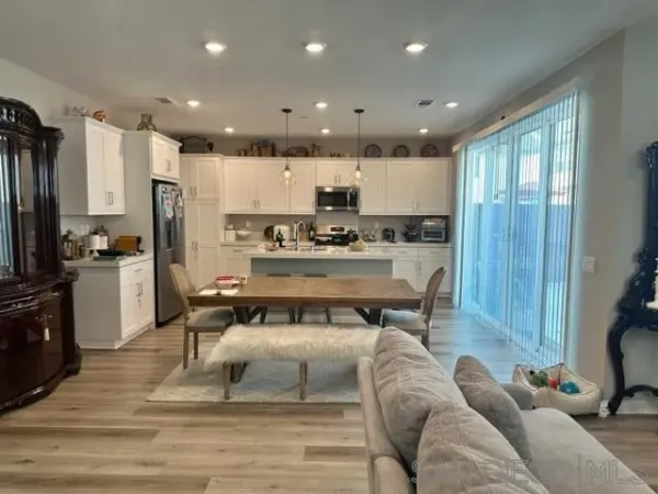 a living room with stainless steel appliances furniture a rug and a kitchen view