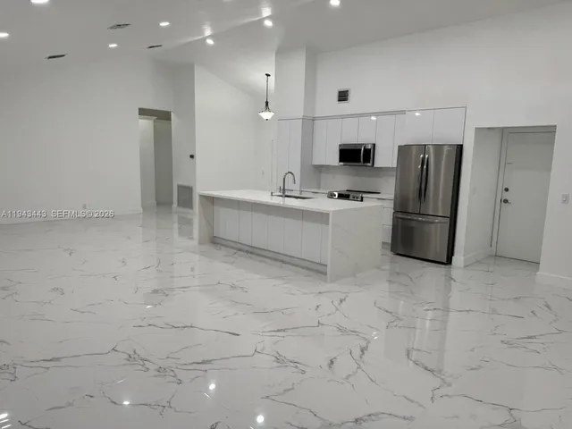 a large white kitchen with a refrigerator and a stove top oven