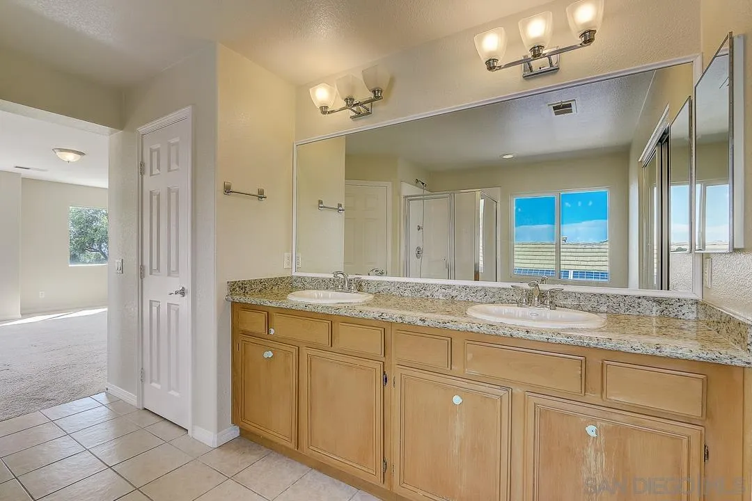 551 Dundee Lane San Marcos, CA 92069 - Photo 23 of 30 a bathroom with a granite countertop sink and a mirror
