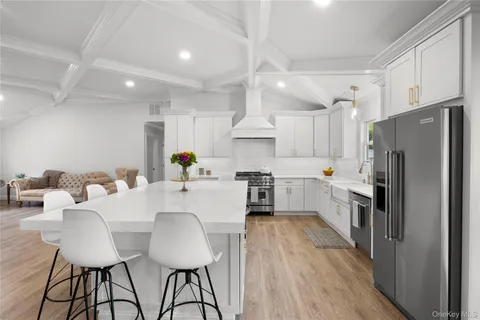 a kitchen with stainless steel appliances a refrigerator a stove a sink dishwasher a dining table and chairs with wooden floor