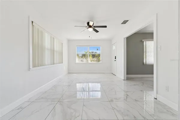 an empty room with windows and ceiling fan