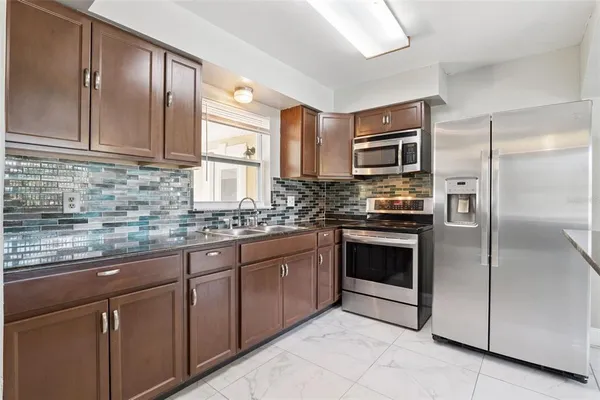 a kitchen with stainless steel appliances granite countertop a refrigerator a stove a sink and dishwasher