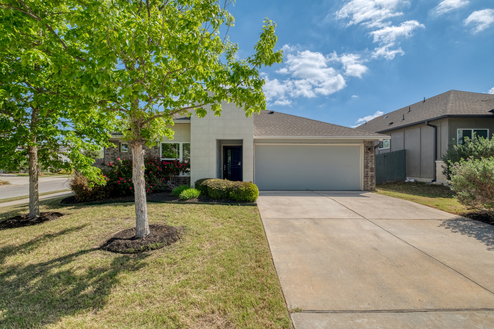 16400 Fetching Avenue Manor, TX 78653 - Photo 2 of 32 View of front of property featuring an attached garage, concrete driveway, a front yard, and brick siding