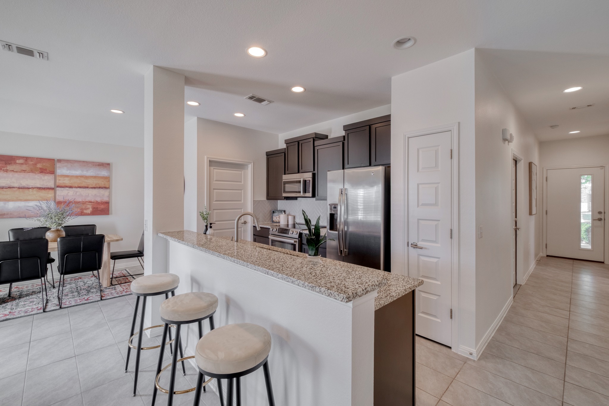 16400 Fetching Avenue Manor, TX 78653 - Photo 8 of 32 Kitchen with stainless steel appliances, light stone counters, light tile patterned flooring, a breakfast bar area, and dark wood finish cabinets