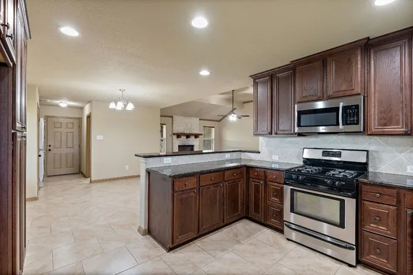 a view of a livingroom with a fireplace a ceiling fan windows and fireplace