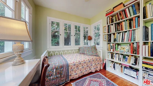a bedroom with a bed a book shelf and a window