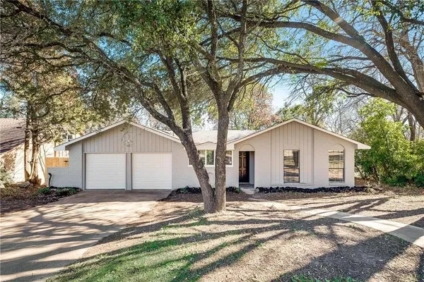 a view of a house with a yard and large tree