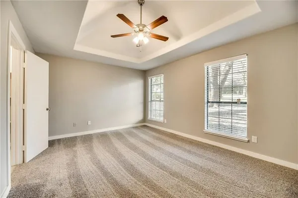 an empty room with windows and ceiling fan